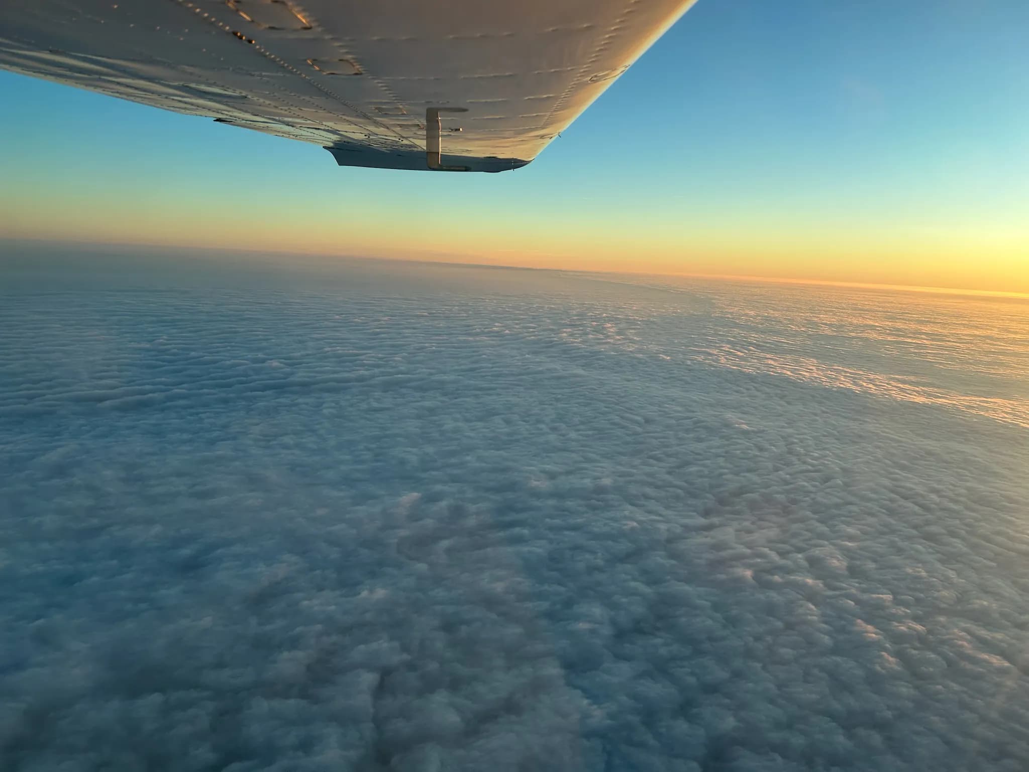 A sea of clouds at sunset, under the wing of the aircraft